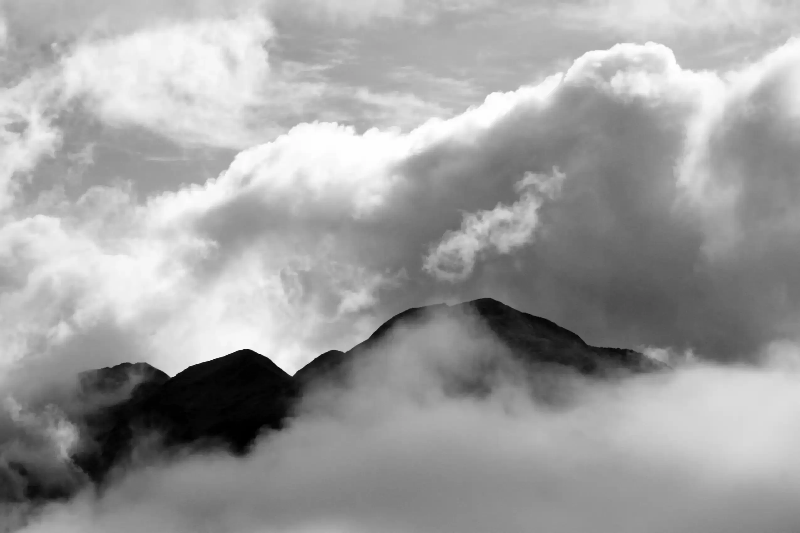 A black-and-white mountain peak emerging from rolling cloud.