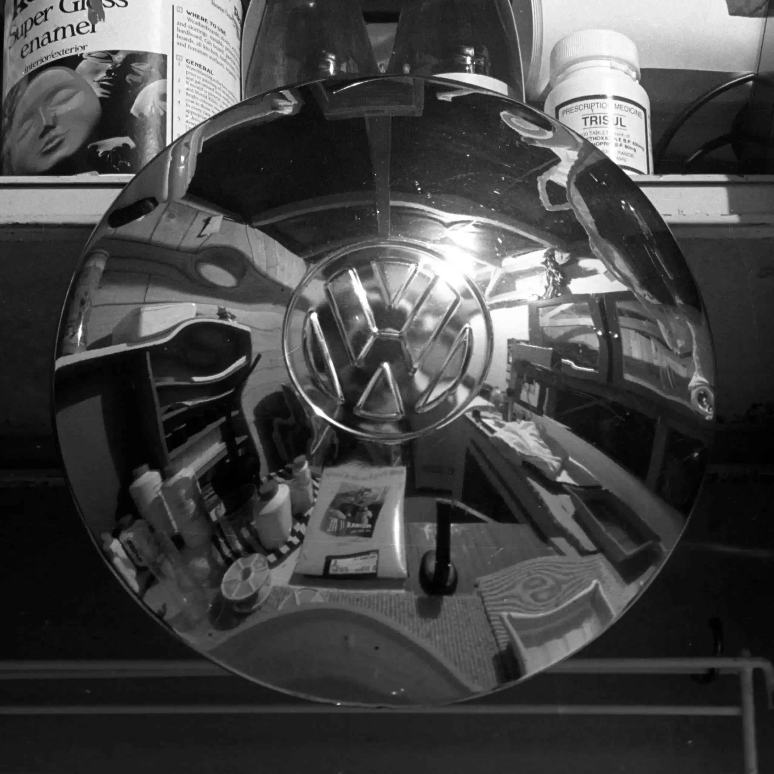 A polished VW hubcap reflecting a darkroom-like interior — a self-portrait from 1999.